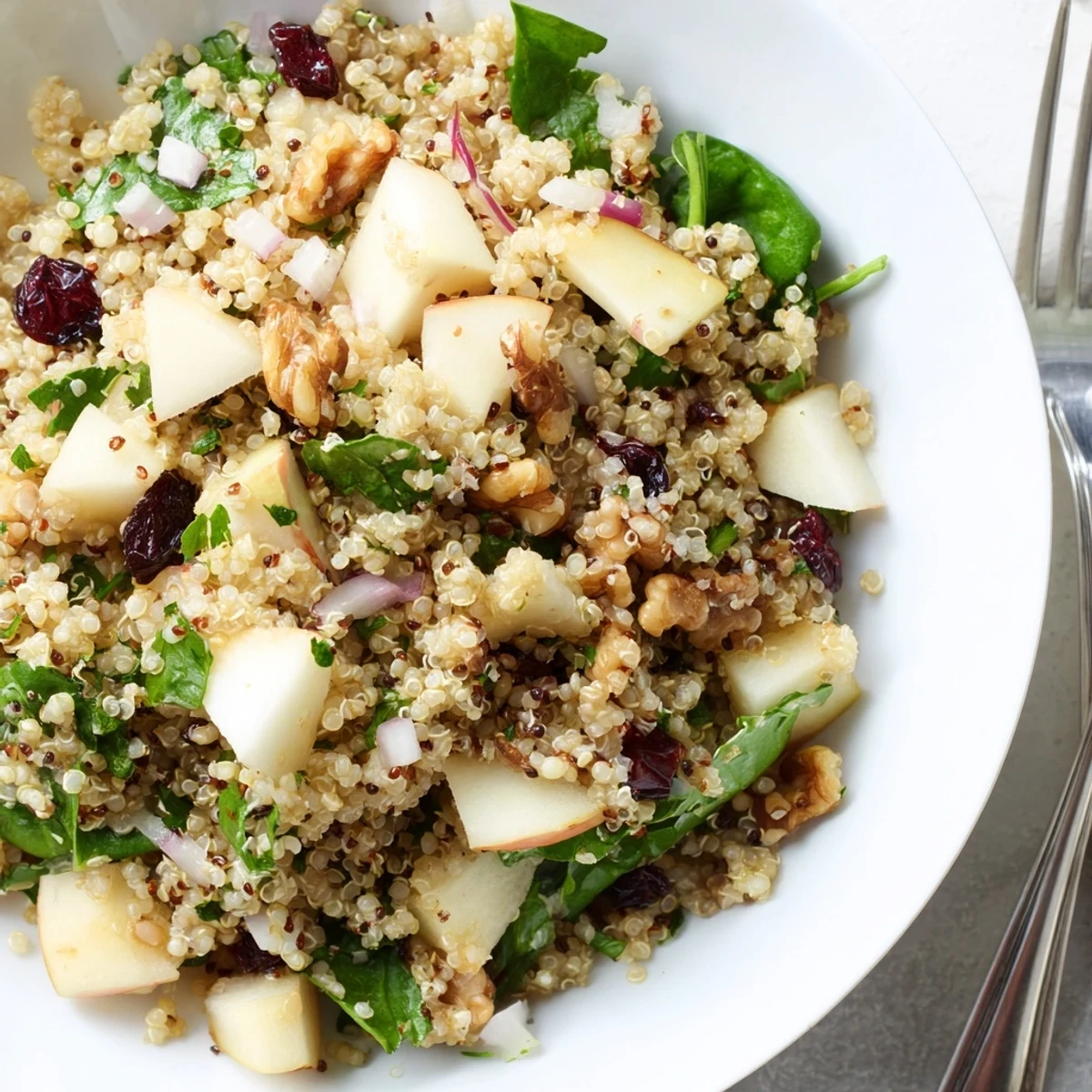 Bunte warme Quinoa-Salat mit Äpfeln, Spinat und Honig-Senf-Dressing serviert.