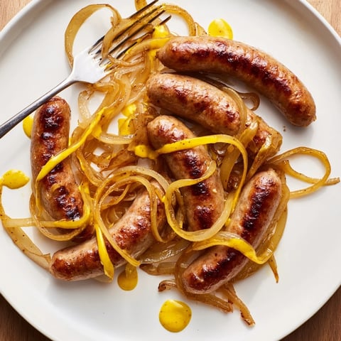 Saftige Bratwürste, goldbraun in der Pfanne gebraten, serviert mit Zwiebeln.